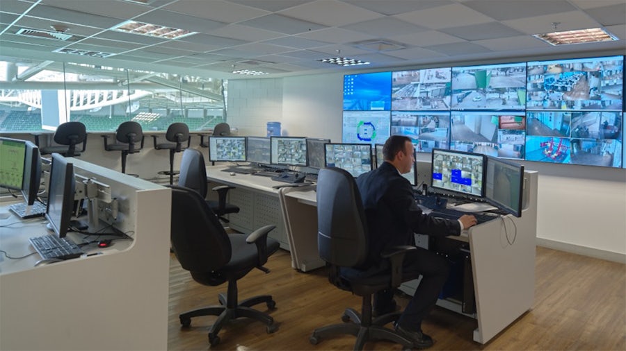 Security professional works at a desk with multiple monitors. 