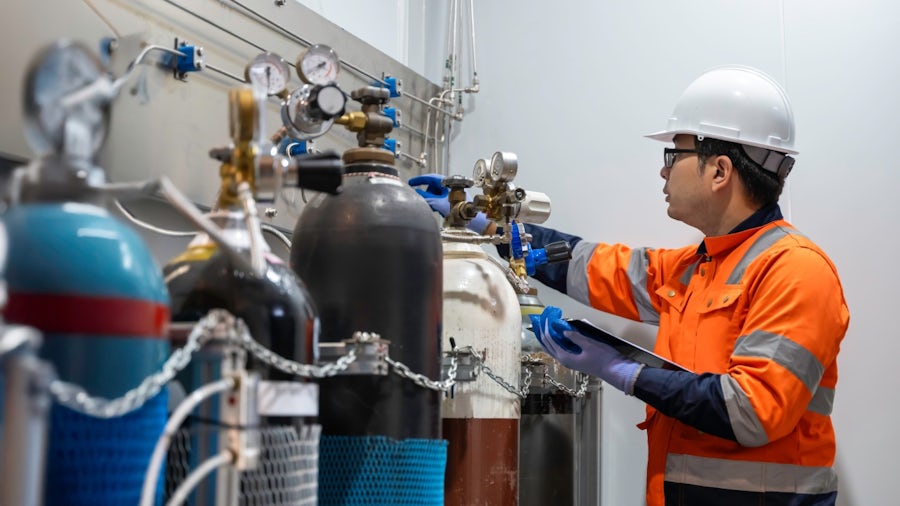 Engineer inspects hydrogen gas cylinders in a manufacturing facility, representing the need for digital tools to streamline complex hydrogen equipment production
