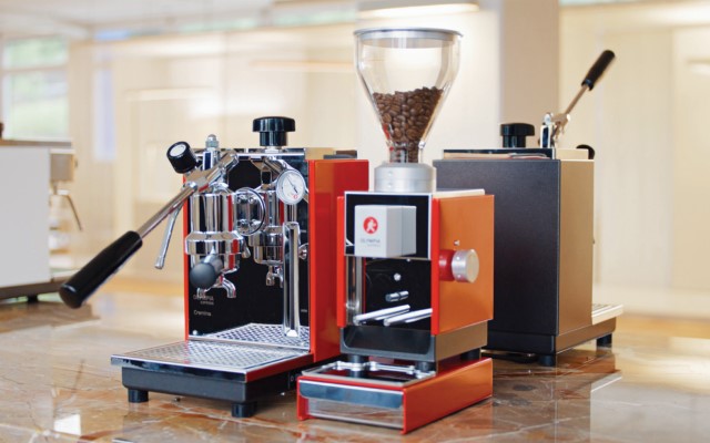 A red espresso maker and orange coffee grinder on a table