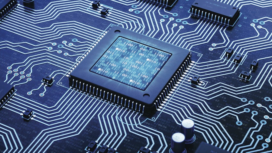 enhanced picture of an integrated circuit on a printed circuit board in a blue hue with white and green traces on the PCB