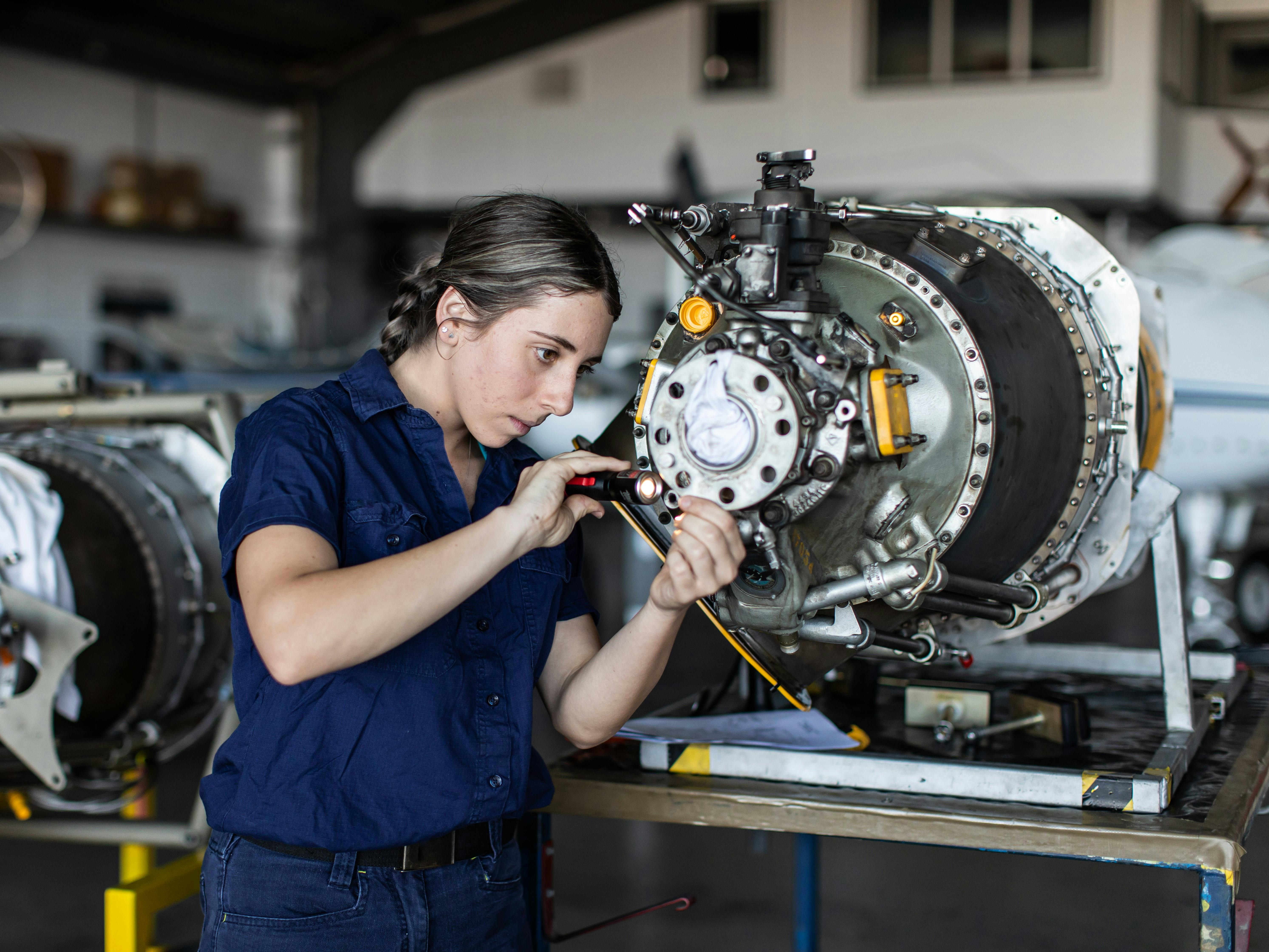 A female engineer works on a large and complex mechanical component.