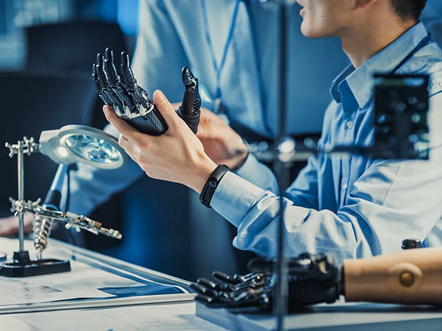 Engineer holding a prosthetic robot arm.