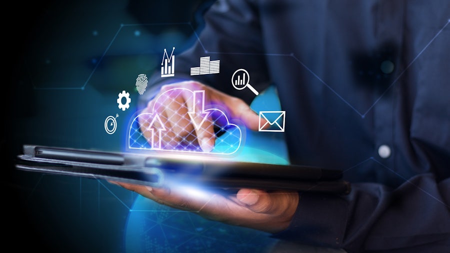 A person interacts with a tablet, displaying a glowing cloud icon with arrows. Surrounding it are icons for email, graphs, and gears, conveying technology and connectivity.