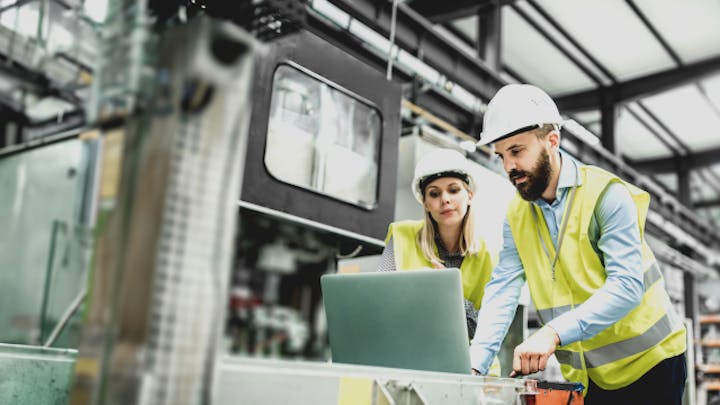 공장에서 컴퓨터로 작업을 하고 있는 두 사람