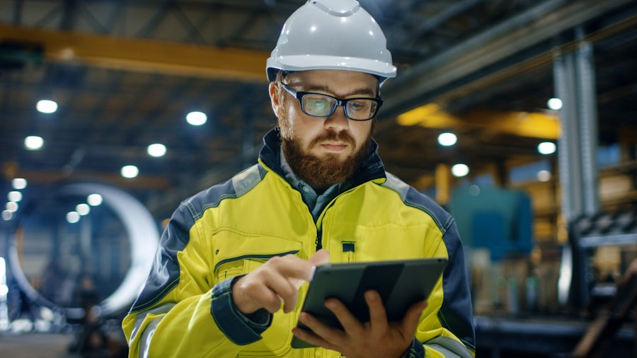 Lavoratore di attrezzature pesanti in un elmetto utilizzando un iPad