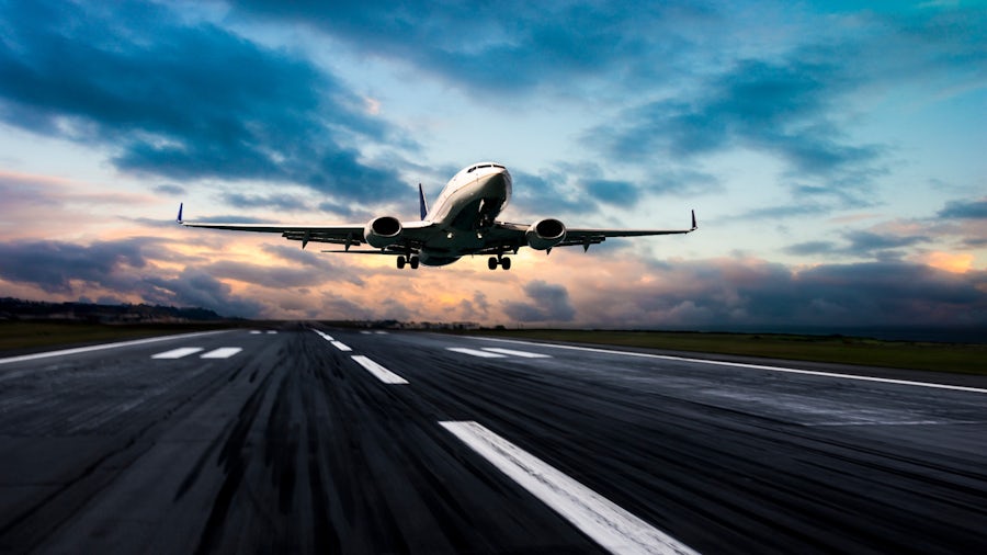A commercial aircraft just off the ground with its landing gear being retracted.