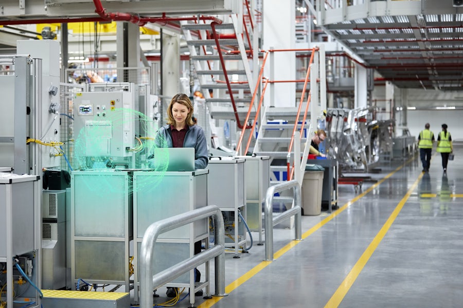 A woman in production hall watching laptop with cognisphere in front of her