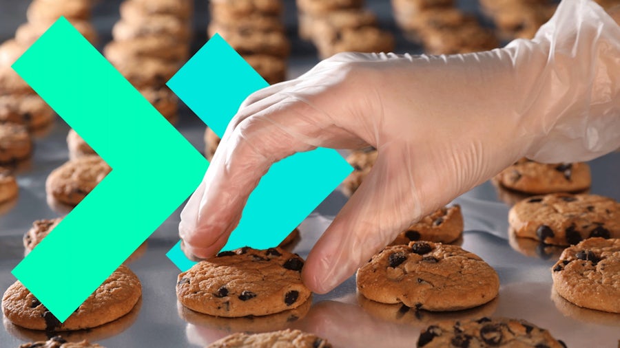 Una mano selecciona una galleta de una línea de producción como símbolo de la fabricación Agile en la alimentación y las bebidas. Se superponen elementos de diseño geométrico para representar la innovación y la flexibilidad en los procesos de fabricación.