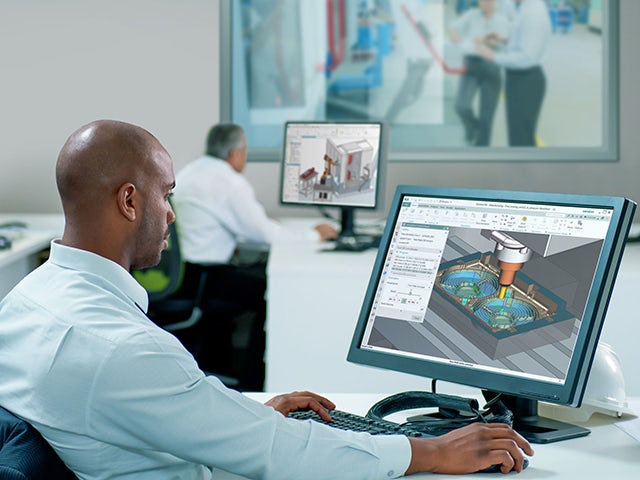 NX CAD 소프트웨어가 표시된 컴퓨터 화면을 보고 있는 남자