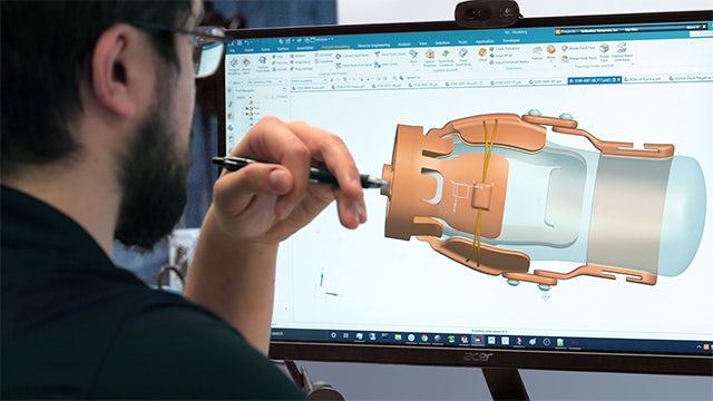 Hombre mirando un diseño de NX en la pantalla de un ordenador