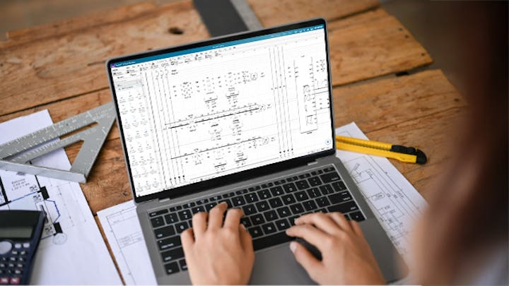 A laptop on table with electrical schematics drawing on the screen.
