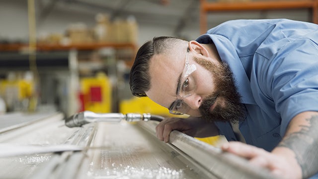 Imagen de un ingeniero que examina la calidad de una pieza de chapa durante la fabricación.