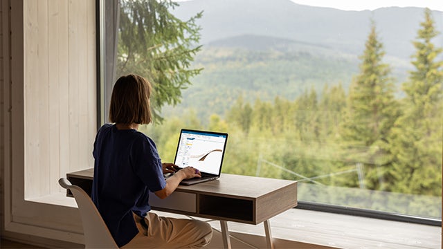 Woman sitting at a computer using NX in front of a large window
