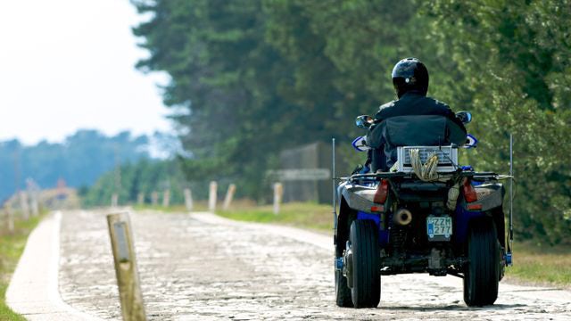 A person driving an ATV down a country road.