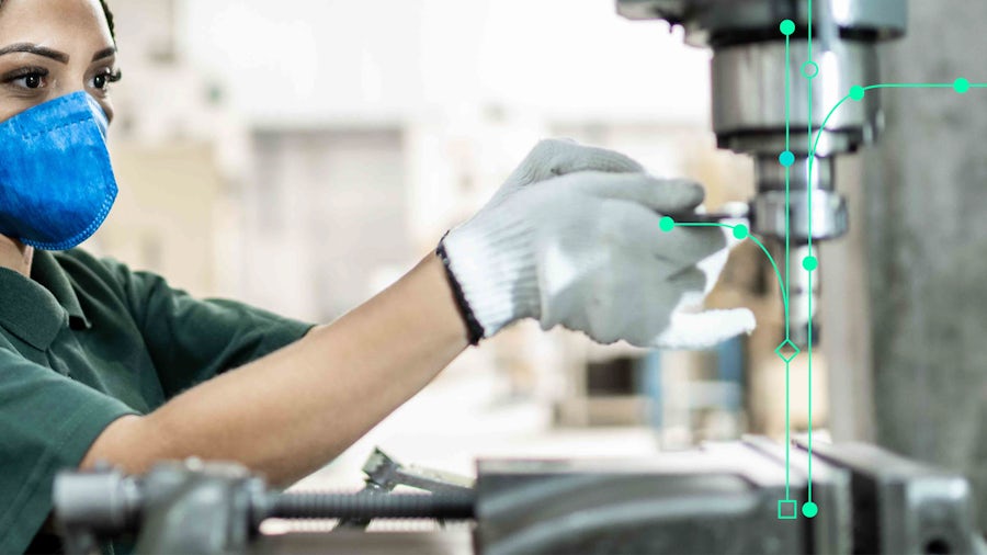 A manufacturing floor operator works on a piece of equipment used to build machine components.