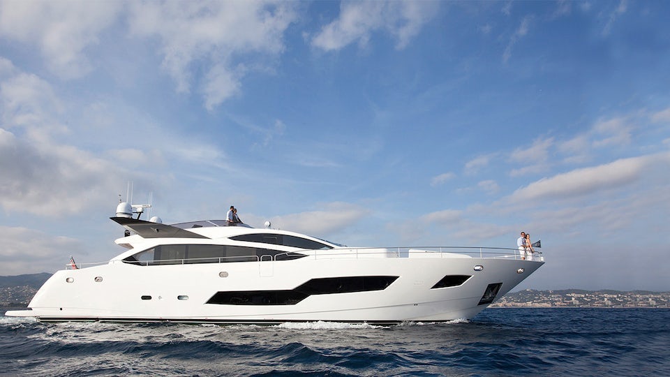 A Sunseeker yacht on the water, with a couple on the ship's bow.