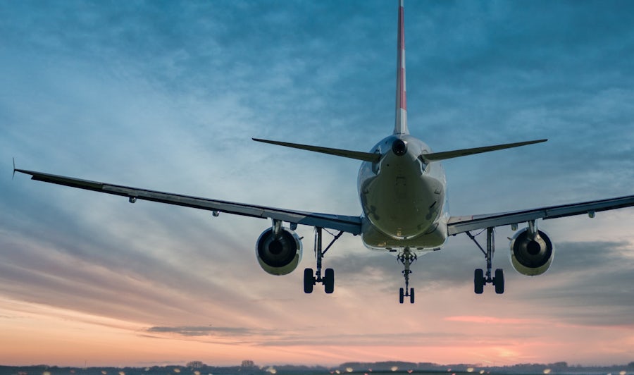 A commercial airplane lands on a runway at sunset.
