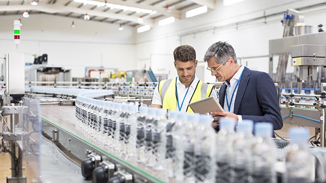 Two engineers working in a bottling plant discussing Insight Hub Solutions.