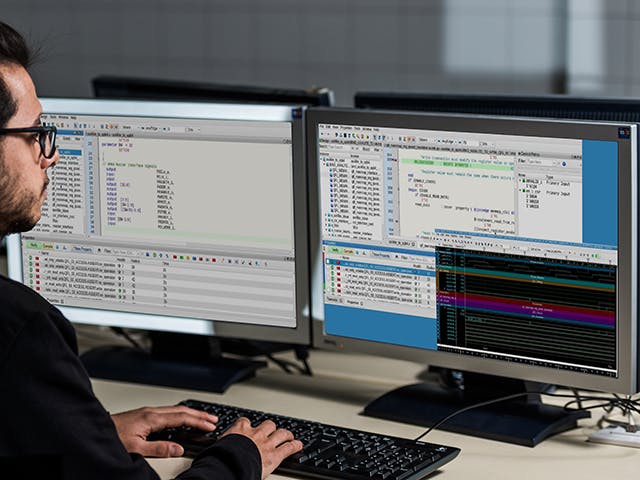 Engineer using Questa Check Register Tool on his two monitors 