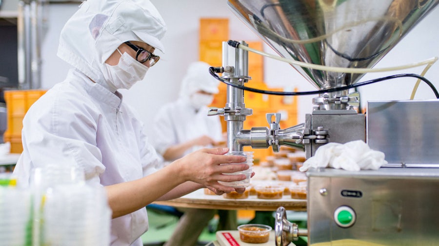 Ouvrier d'usine tenant un conteneur contre une machine dans une usine