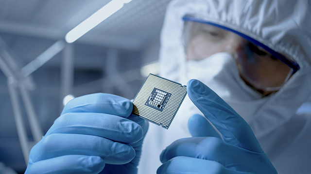 Osoba v ochranném obleku, která v ruce drží počítačový procesor
