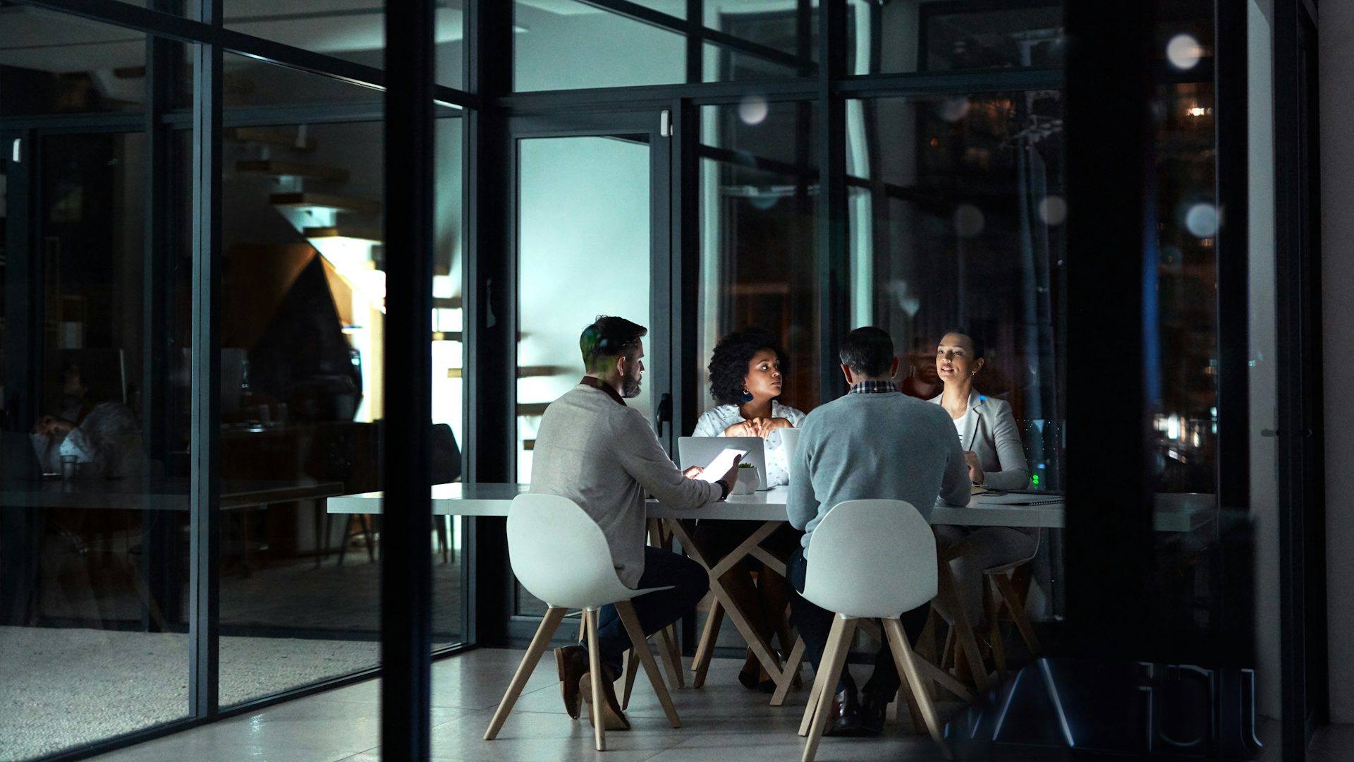 Four people are sitting at a desk working and discussing something.