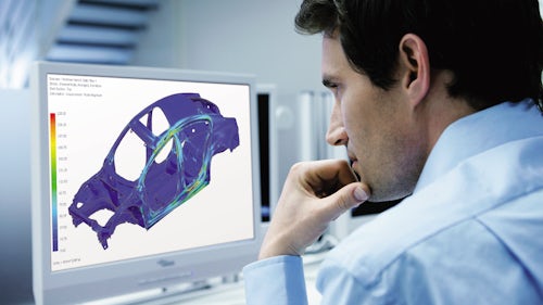 Engineer at a computer screen running a structural simulation of a car body in Simcenter 3D.