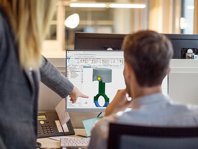 Pracownicy omawiają modelowanie części bryłowych i złożeń w oprogramowaniu NX Core Designer wyświetlanym na komputerze.