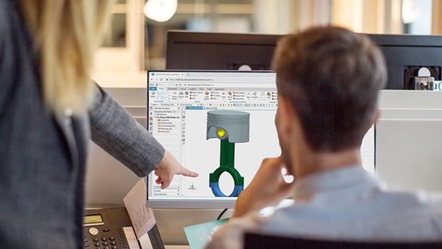 Viewing a computer, workers discuss solid part and assembly modeling in NX Core Designer.