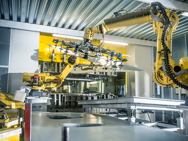 Car parts being handled by yellow robots in a car factory.