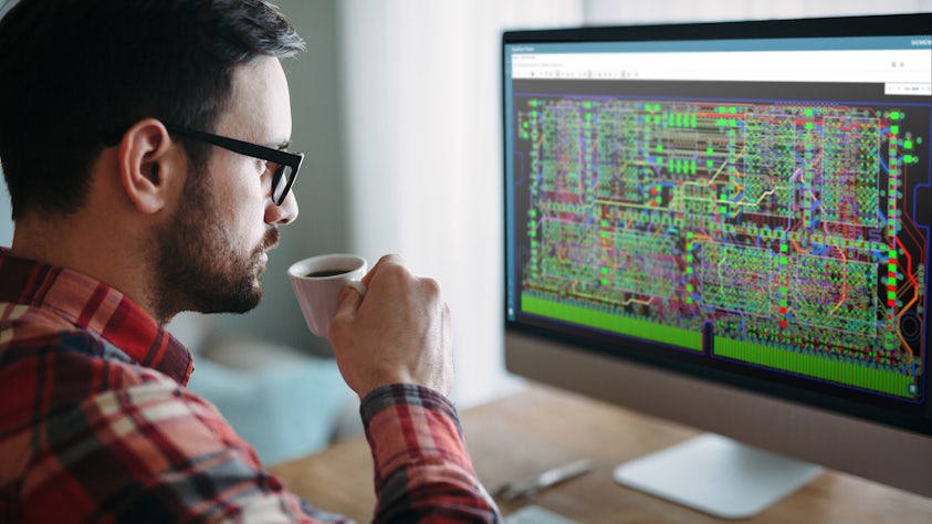 With coffee in hand, an engineer studies data on a monitor.