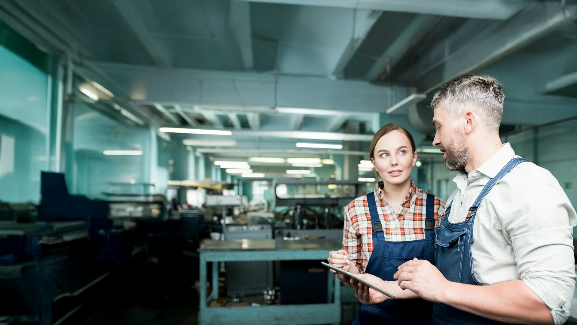Two people in a machine shop working on a tablet device.