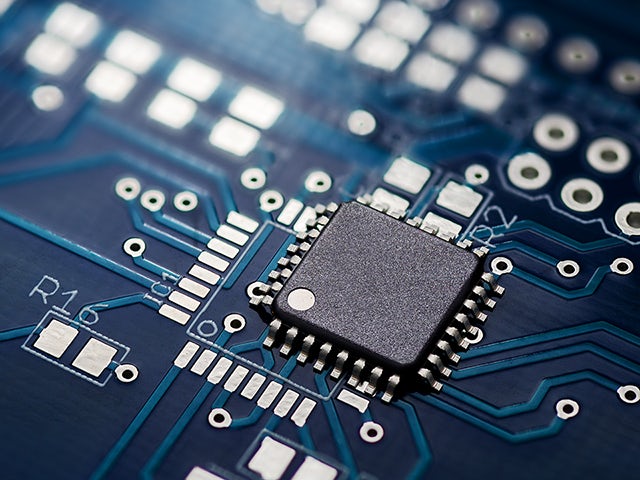 Close-up view of an electronic chip on a blue printed circuit board.