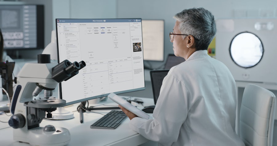 A scientist in a lab coat observes a sample under a microscope, focused on his research in a laboratory environment.