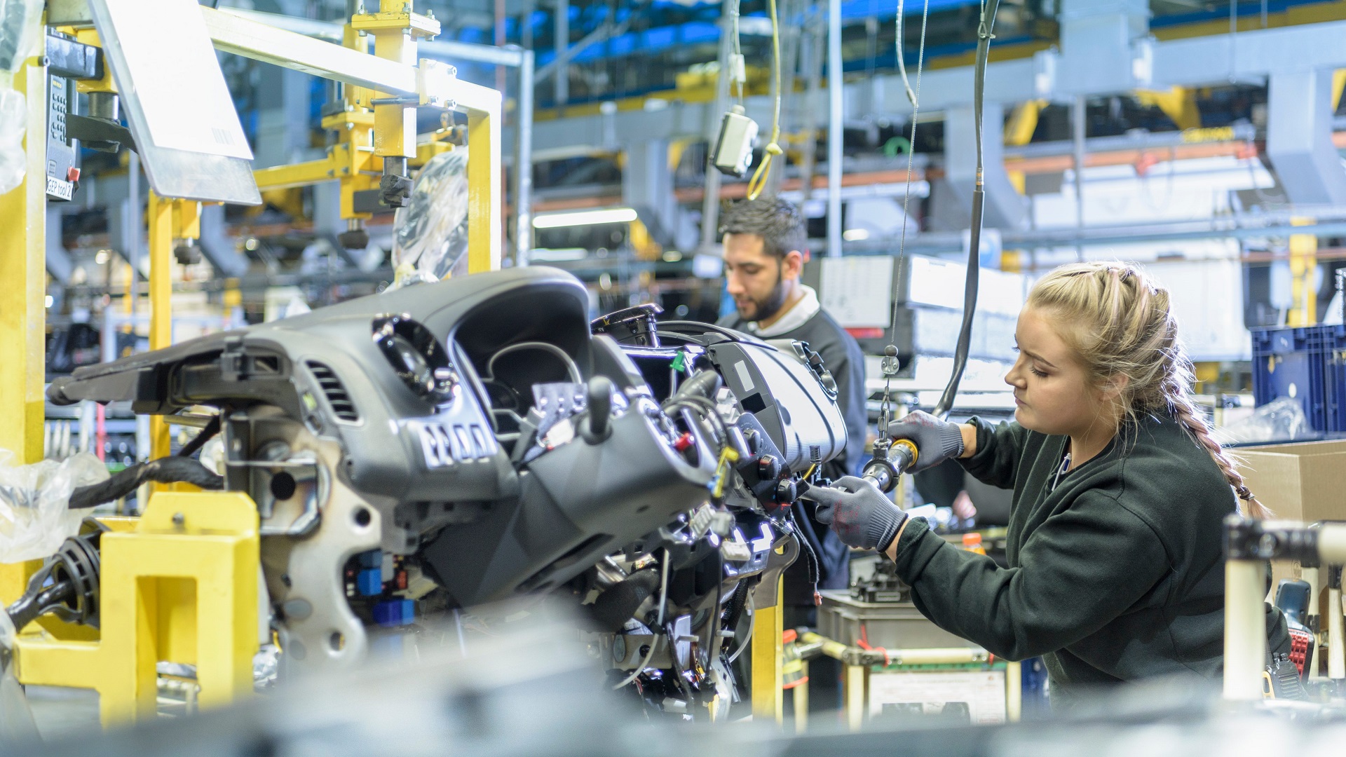 Factory workers build car engines on an assembly line