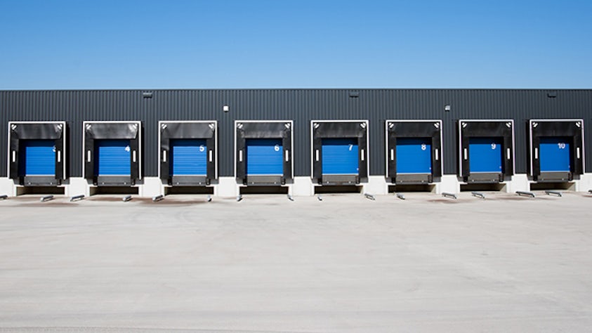 A warehouse loading dock or flush dock with eight blue trailers.