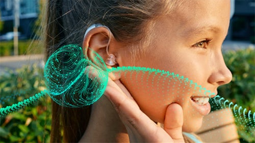 Bild eines Mädchens mit einer Hörhilfe im Ohr