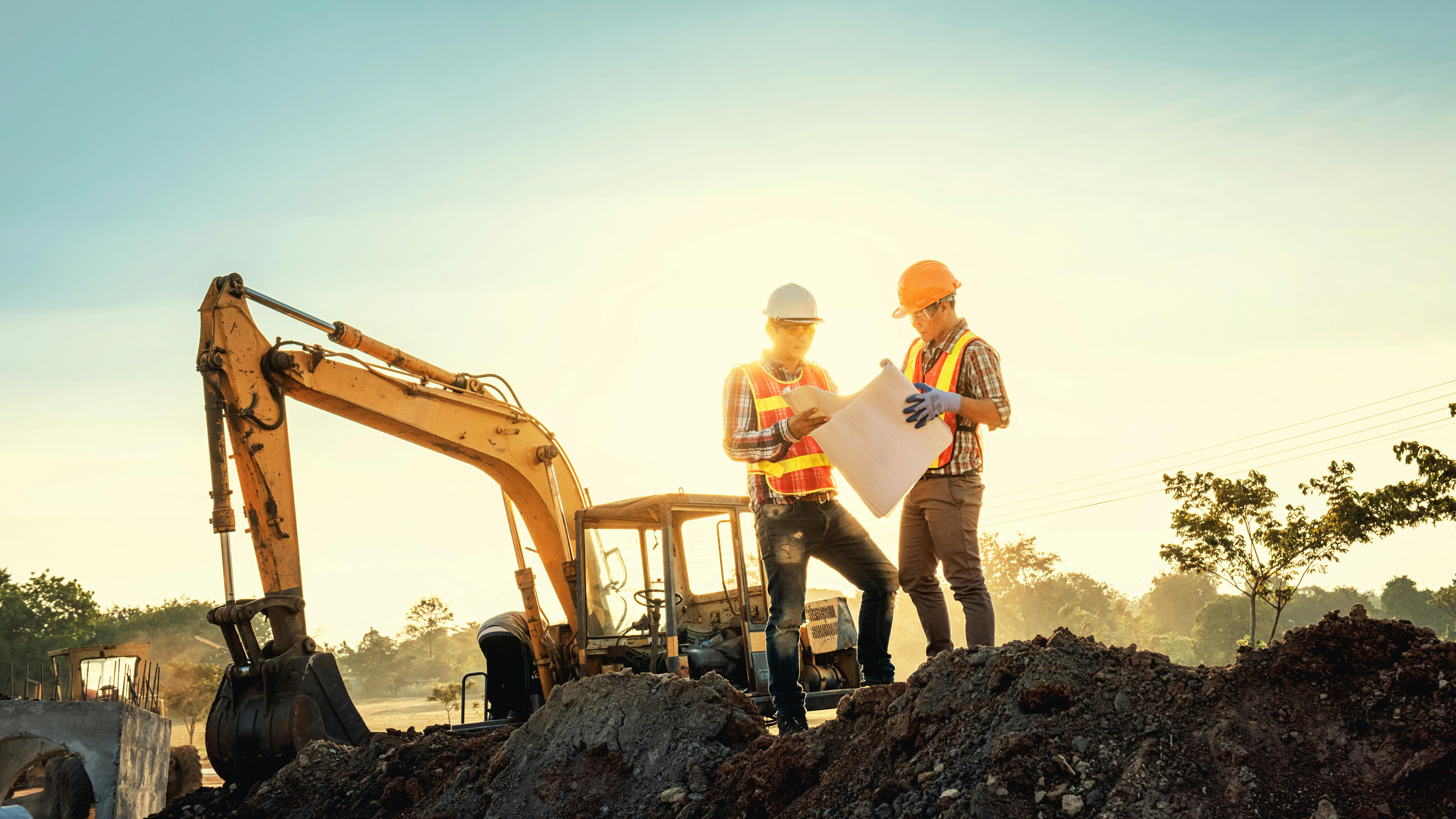 Two engineers at a construction site looking at a blueprint