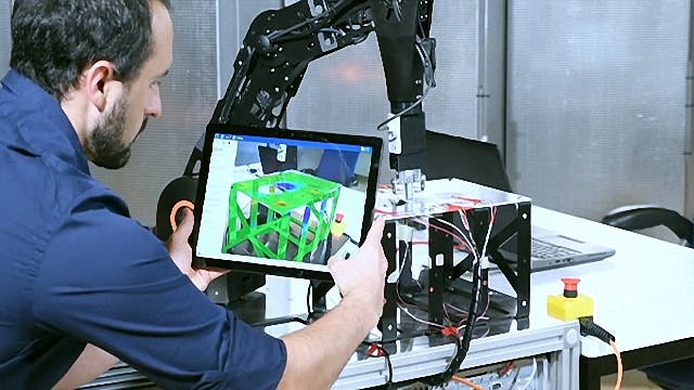 An engineer uses an executable digital twin (xDT) on a tablet to analyze the performance of an industrial machine in operation.