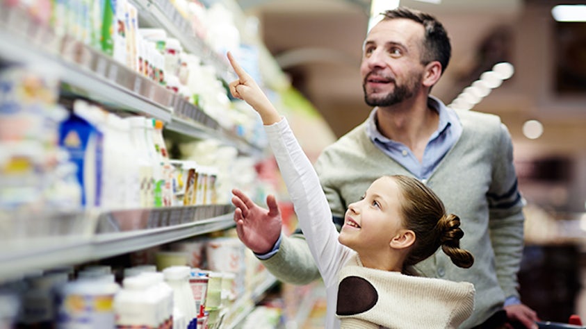 Un hombre y una niña examinan productos de consumo en un supermercado.
