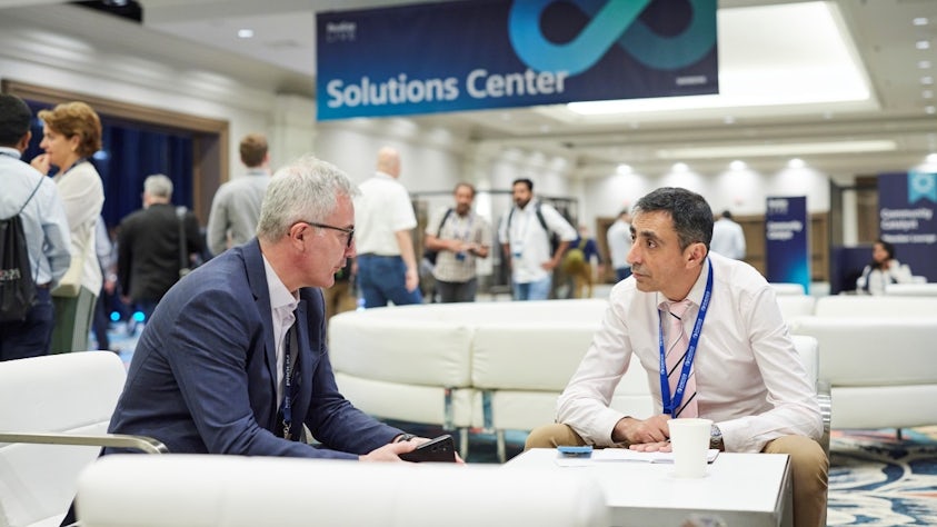 Two conference attendees have a discussion in the Siemens Realize LIVE Connection Lounge.