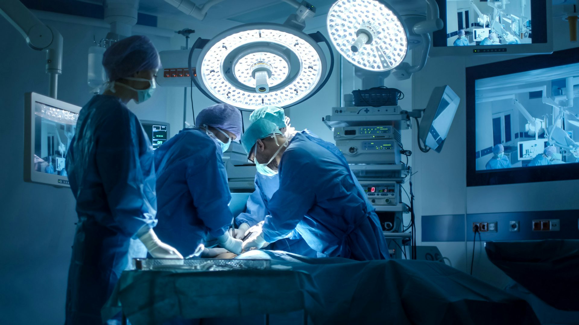 Chirurdzy wykonujący operację na sali operacyjnej: Zespół wykwalifikowanych chirurgów przeprowadzających zabieg medyczny w sterylnej sali operacyjnej.