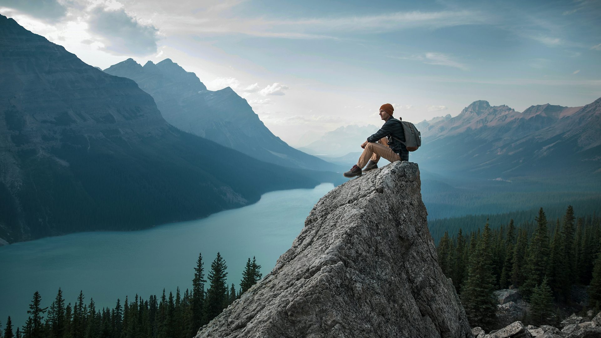A man at the top of a mountain observes the landscape. 