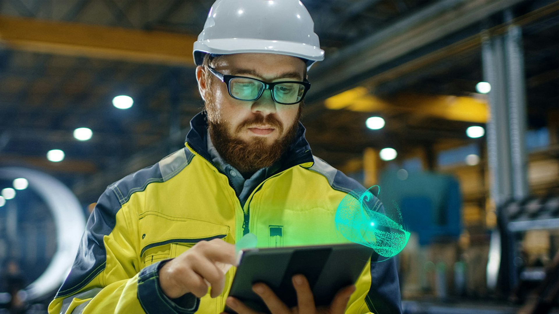 A man in a hardhat looks at a tablet that is emanating green graphics