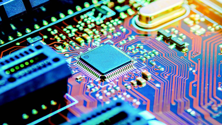 Integrated circuit on a blue hued printed circuit board with traces in orange, white and red on the PCB