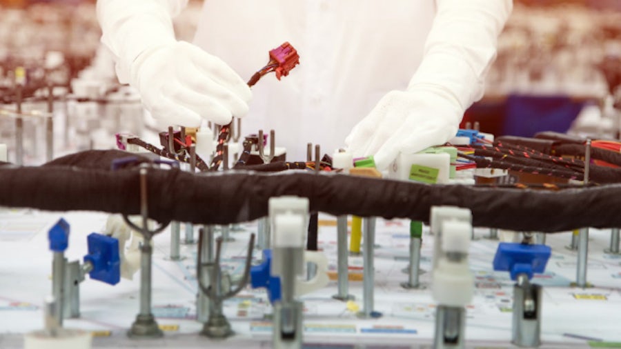 A wire harness manufacturing engineer working with an optimized formboard drawing on the production line.
