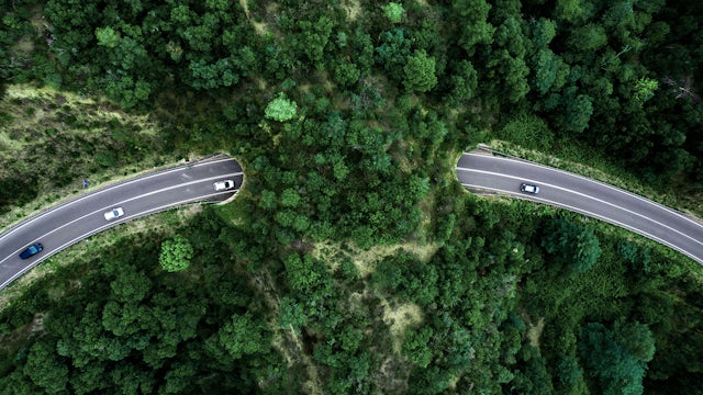Aerial view of a road curving through green landscape.