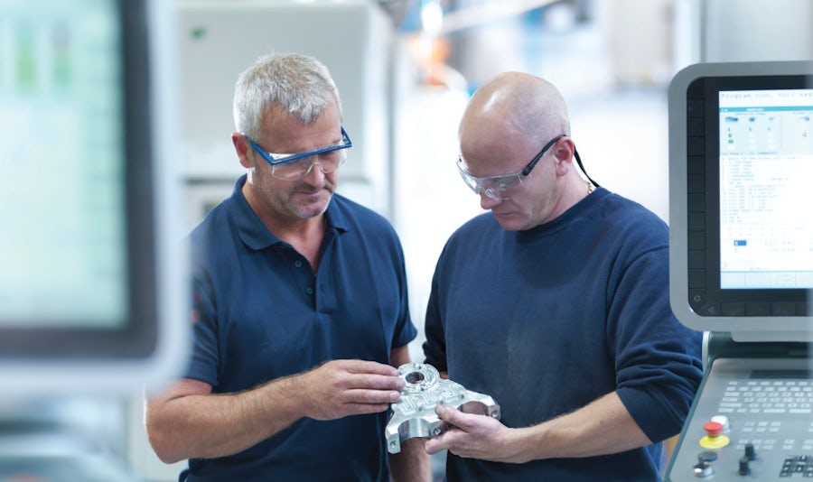 Zwei Personen mit Schutzbrillen und marineblauen Hemden halten ein Metallstück zur Begutachtung. Erfahren Sie auf der Zel X-Website, wie Sie die Angebotserstellung, Beschaffung und Produktion in der Fertigung beschleunigen können. .