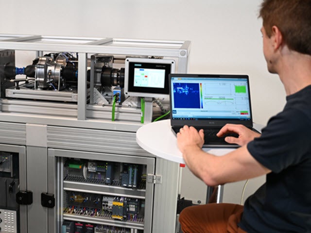 Mechatronic systems testing and analysis being performed by an engineer using advanced test bench with dual monitors and control equipment.