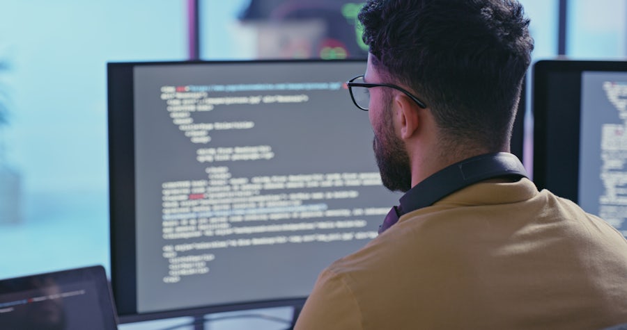 man writing code on monitor